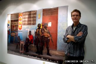 Photographer Darren Ell stands by one of three photos of his exhibition <em>Haiti: Holdup</em>, now on display at the Media Gallery in the CJ Building.